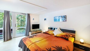 Une chambre à coucher avec un lit, une télévision, une table de chevet et un tableau au mur.