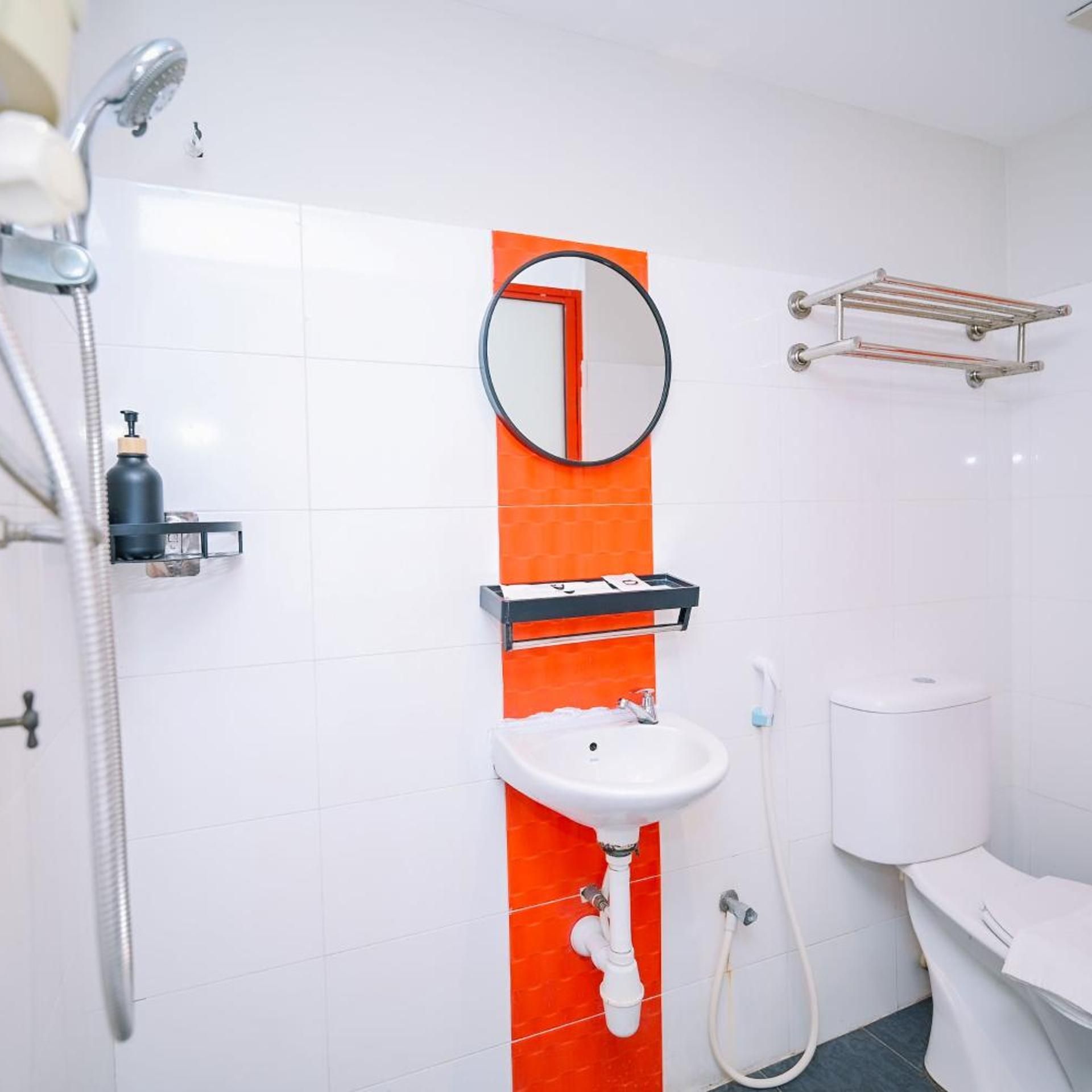 A bathroom with a white sink, a mirror, a shower, and a toilet.