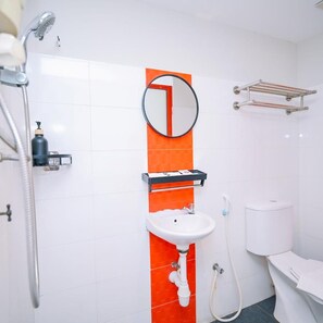 Une salle de bain avec un lavabo blanc, un miroir, une douche et des toilettes.