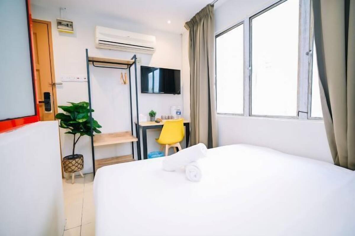 Een hotelkamer met een bed, een bureau, een stoel, een televisie en een raam.