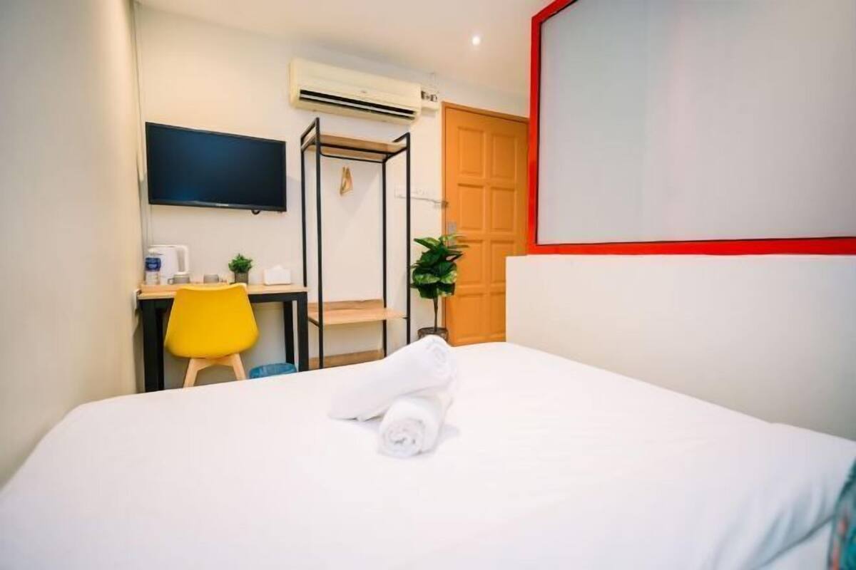 Een hotelkamer met een bed, een bureau, een stoel, een televisie en een airconditioning.