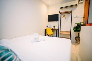 A hotel room with a bed, a desk, a chair, a television, and a potted plant. - Swing & Pillows @ KL Kuchai Lama (Kuala Lumpur)