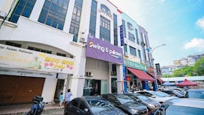 Un immeuble à plusieurs étages abritant divers commerces, notamment un restaurant et un magasin appelé « Swing & Pillows ».