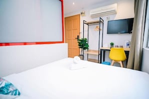 Ein Hotelzimmer mit Bett, Schreibtisch, Sessel, Fernseher und Klimaanlage.