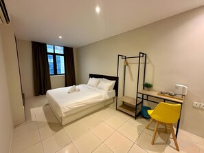 A hotel room with a bed, a desk with a chair, a window, and a bedside table. - Swing & Pillows @ KL Kuchai Lama (Kuala Lumpur)