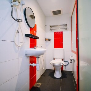 Une petite salle de bain avec un lavabo blanc, des toilettes et un miroir.