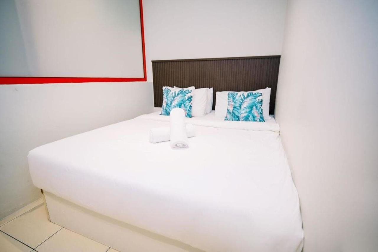 Una habitación de hotel con cama, almohadas y un espejo fijado a la pared.