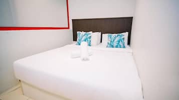 A hotel room with a bed, pillows, and a wall-mounted mirror.