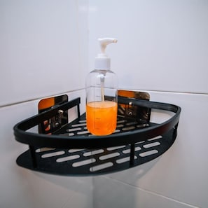 Un baño con un dispensador de jabón negro en una pared de azulejos blancos.