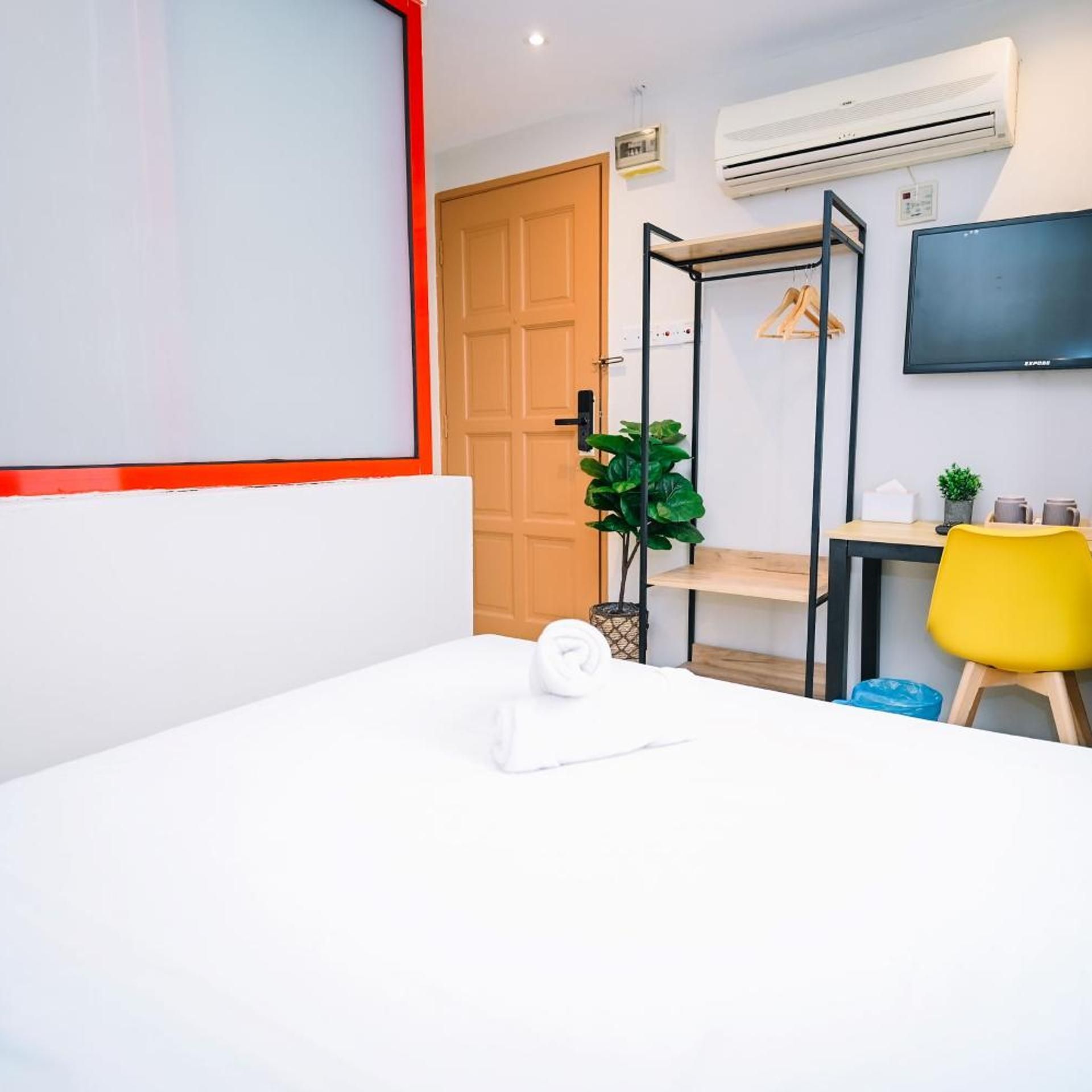 Ein Hotelzimmer mit Bett, Schreibtisch, Stuhl, Fernseher und Klimaanlage.