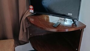 Televisor sobre un suport de fusta amb un comandament a prop.
