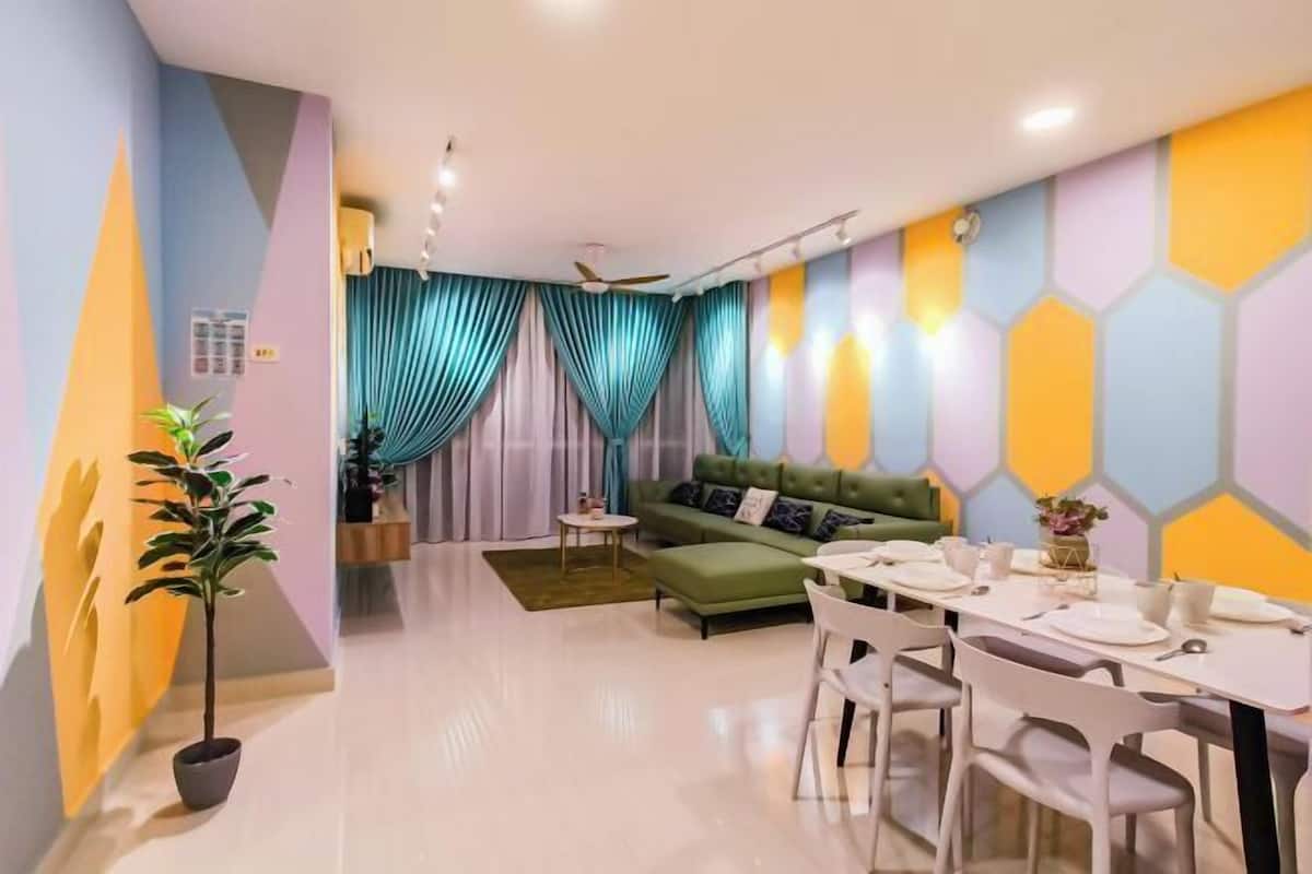 Una sala moderna con un sofá verde, una mesa de comedor con sillas y un ventilador de techo.