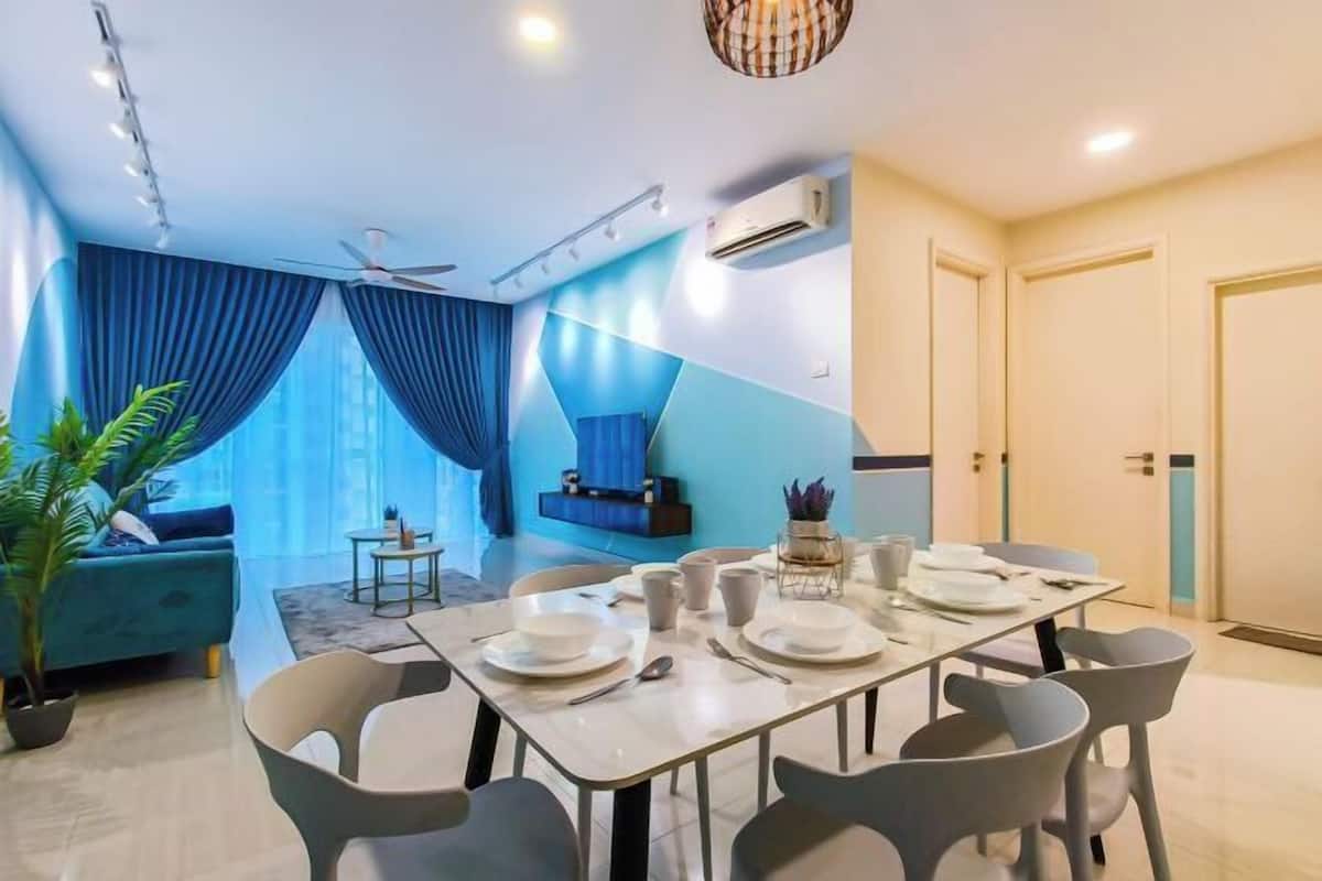 Un comedor con una mesa dispuesta para cuatro personas, un sofá azul y un ventilador de techo.