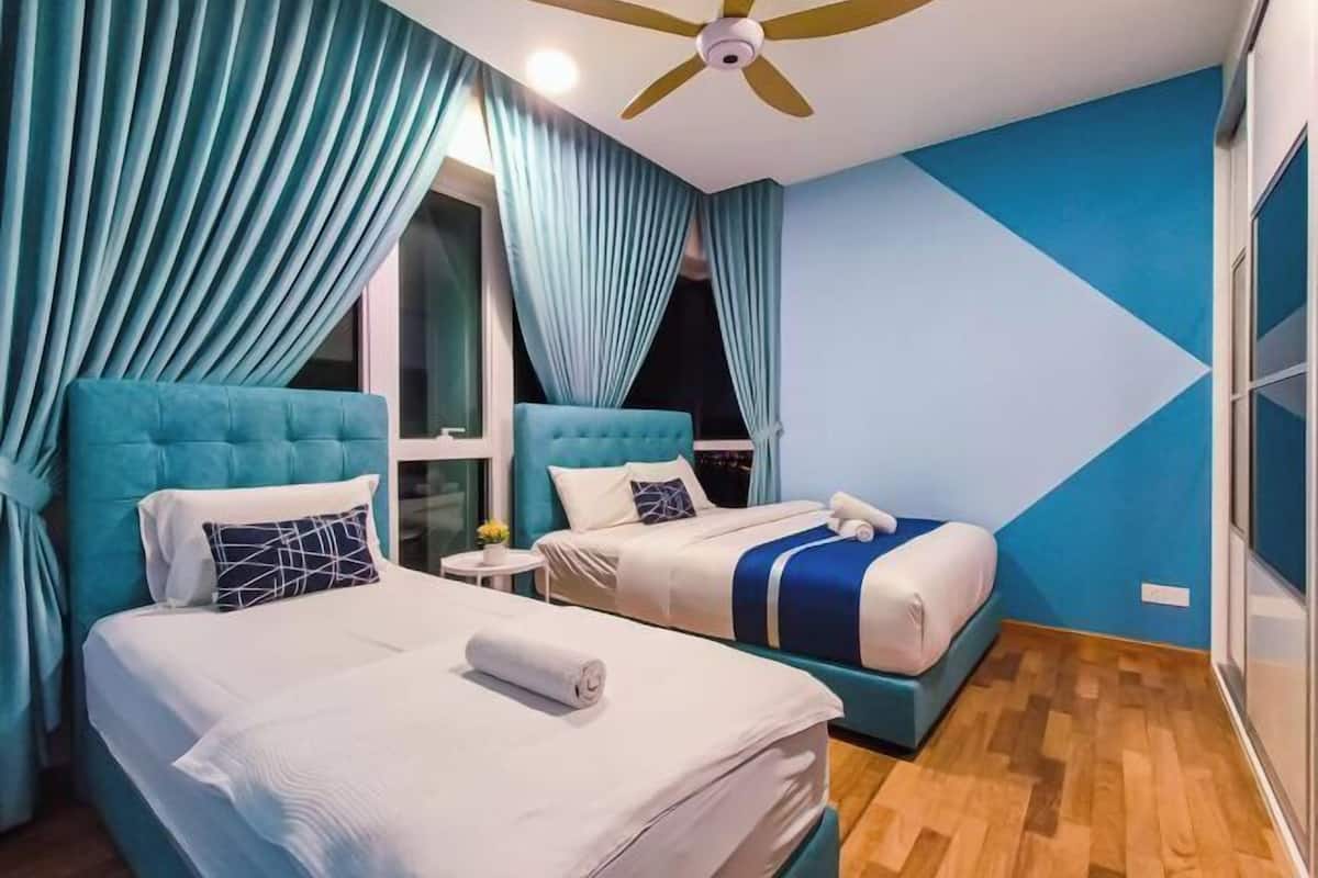 Habitación de hotel con dos camas, ventilador de techo y un gran ventanal con cortinas.