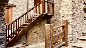 A stone building with a wooden staircase and a wooden gate.
