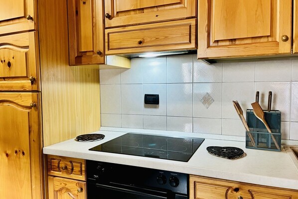 Una cocina con gabinetes de madera, encimera blanca, lavavajillas negro y estufa.