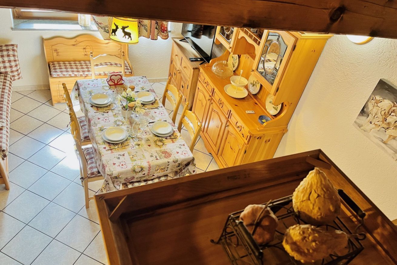 Ein Essbereich mit Tisch für zwei Personen, Holzschränken und einer sichtbaren Küchenzeile im Hintergrund.