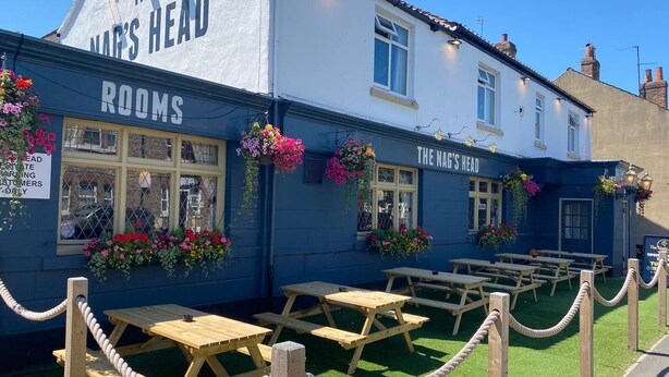 A building with the sign "The Nag's Head" and "Rooms" indicating it is a pub with available rooms. There are outdoor wooden picnic tables arranged in rows. - The Nags Head (York)