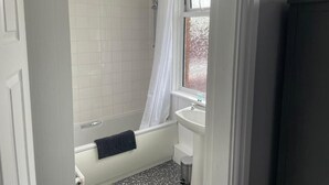 A bathroom with a bathtub, a shower, a window, and a sink. - The Nags Head (York)