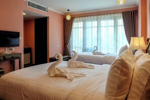 A hotel room with two beds, a TV, a desk, and a window with curtains. - Siri Heritage Bangkok Hotel (Bangkok)