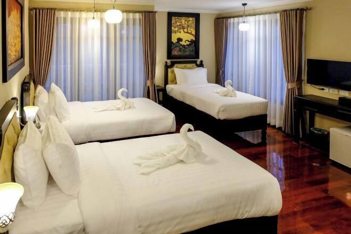 A hotel room with two beds, a flat-screen TV, and a painting on the wall.
