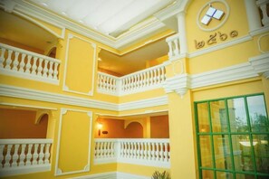 Un interior de varios niveles con balcones y un ventanal verde.