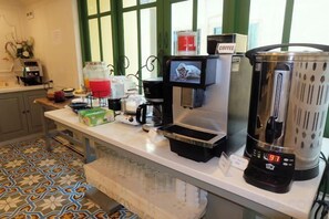 Un plan de travail de cuisine avec une machine à café, un mixeur et un distributeur de café.