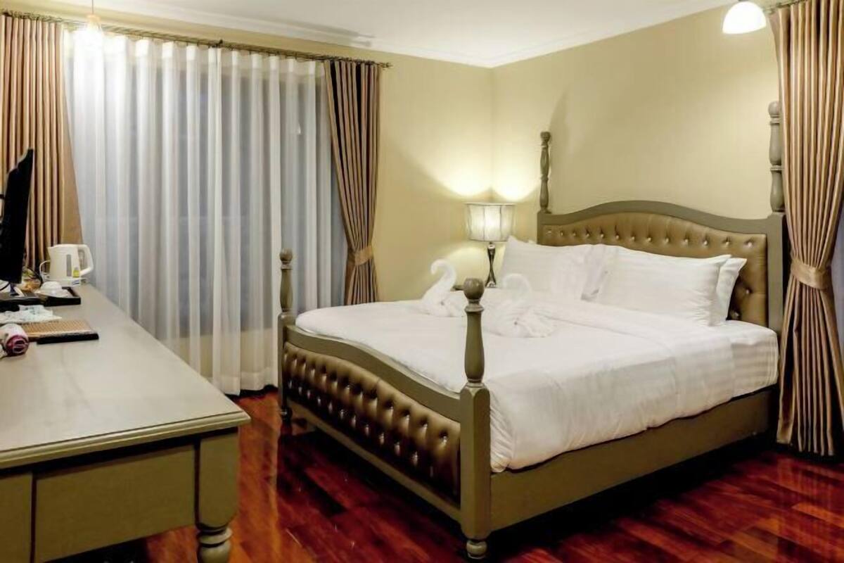 A hotel room with a bed, a desk, and a lamp.