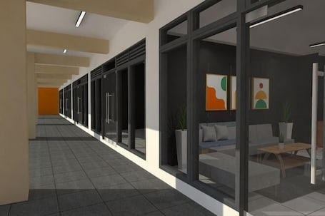A corridor with glass doors, a reception area with a sofa and table, and artwork on the walls.. The City Flats Circuit Makati