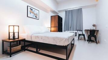 Un dormitorio moderno con cama, mesita de noche, lámpara y escritorio con silla.