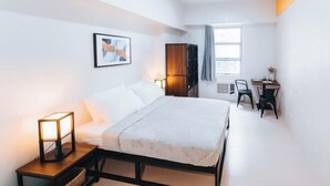 Une chambre d’hôtel moderne équipée d’un lit, d’une table de chevet, d’une lampe, d’une armoire, d’un bureau et d’une chaise.