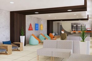 A modern lobby with seating areas, a reception desk, and a visible kitchen area. - The City Flats Circuit Makati (Makati)