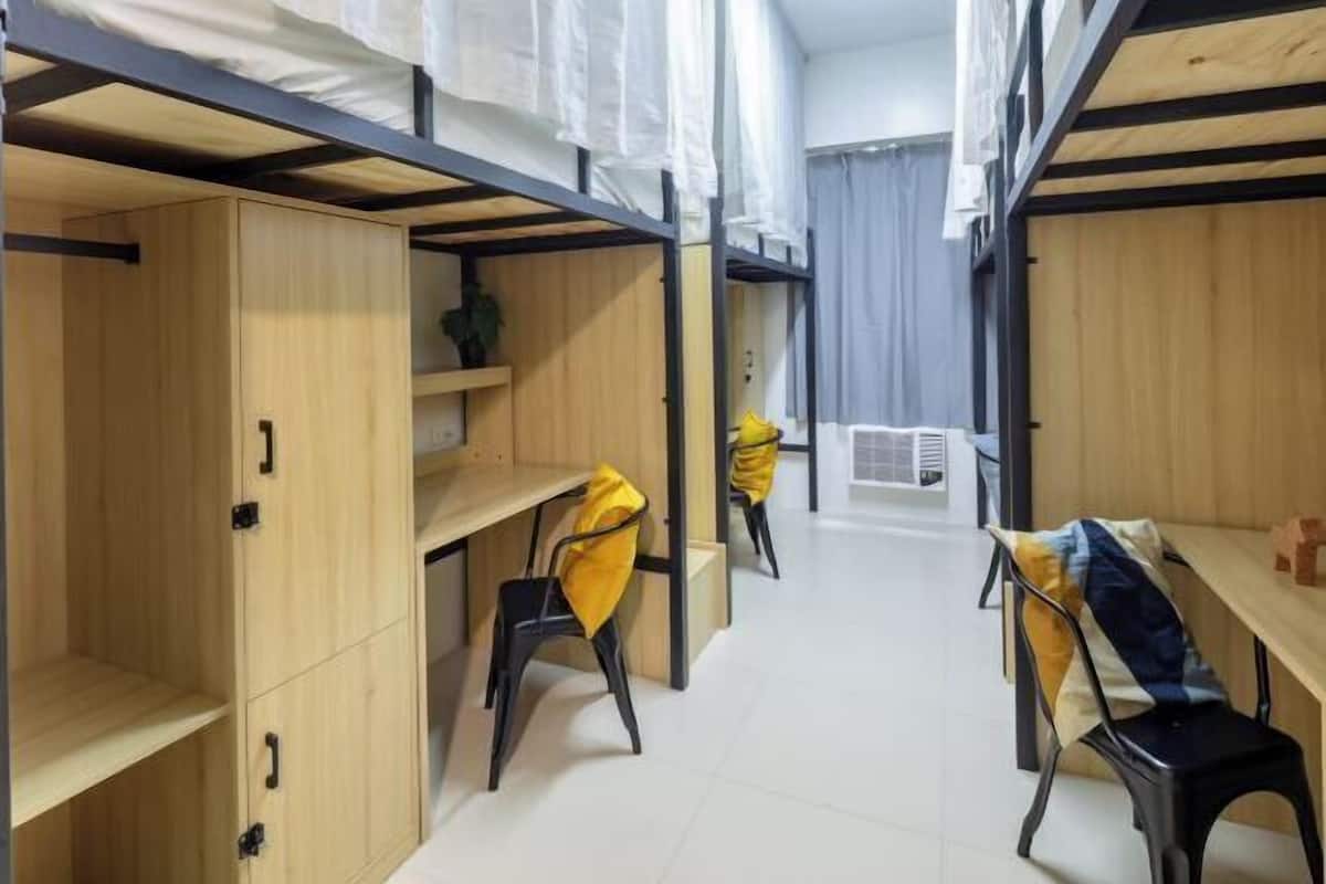 Un dormitorio con literas, armarios de madera y sillas.