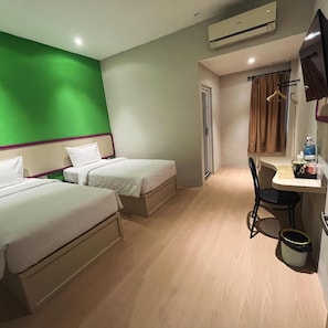 A hotel room with two beds, a desk, a chair, an air conditioning unit, and a bathroom door. - Rumaruma Hotel Kenten Palembang (Palembang)