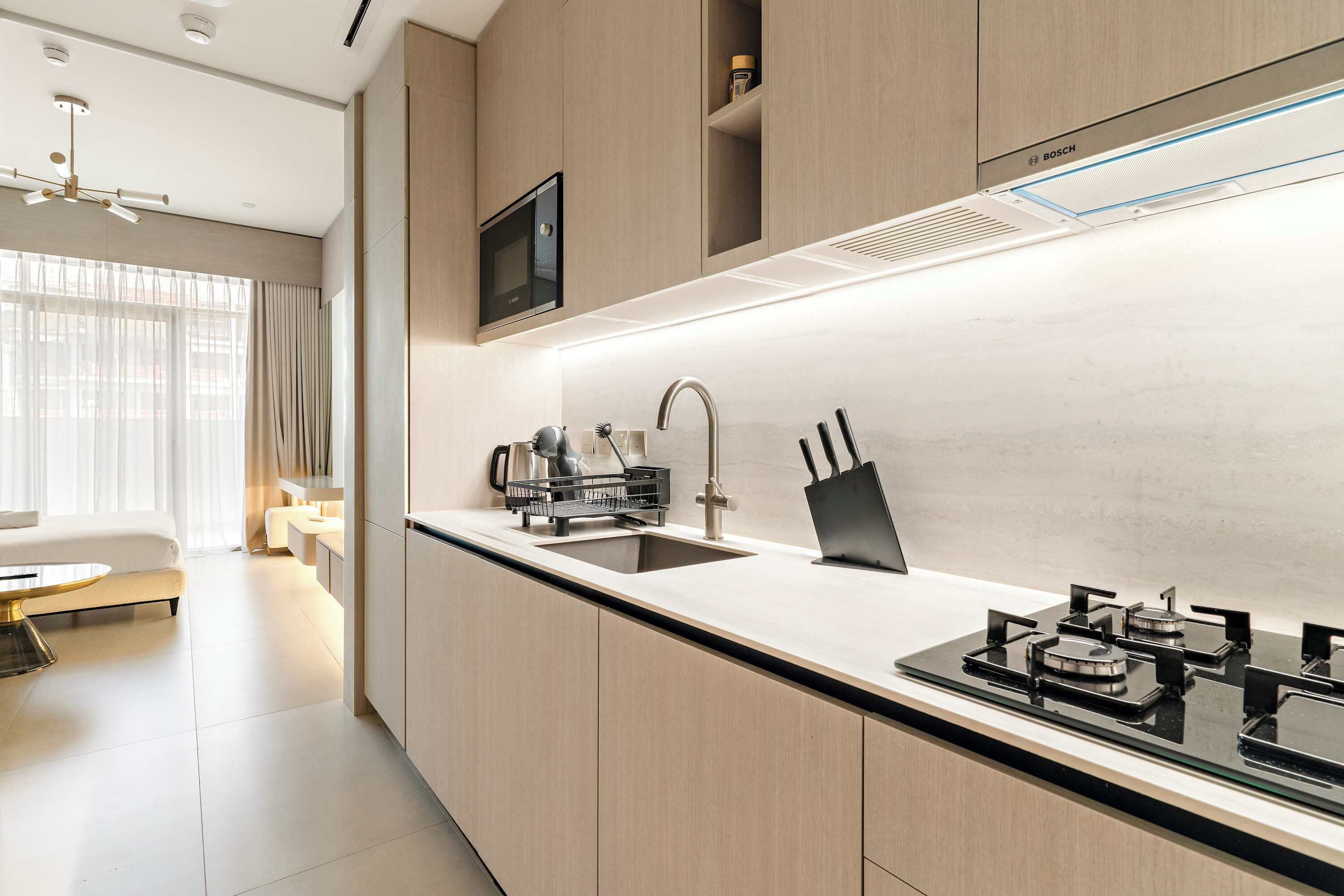 Una cocina moderna con estufa integrada, pileta y un televisor de pantalla plana sobre la encimera.