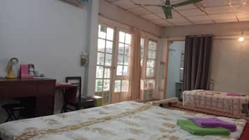 Quarto de hotel com cama, escrivaninha, cadeira, janela e porta.