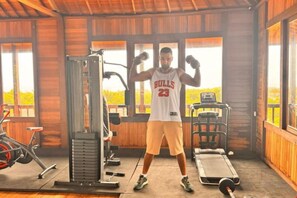 A gym with exercise equipment and a person wearing a Bulls jersey. - Pandawa Beach Homestay 1 (Bali)