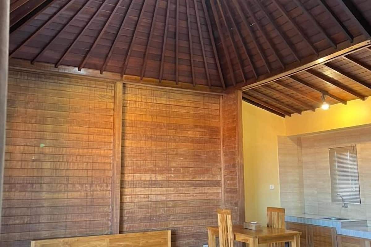 A wooden interior with a high ceiling and a kitchen area.