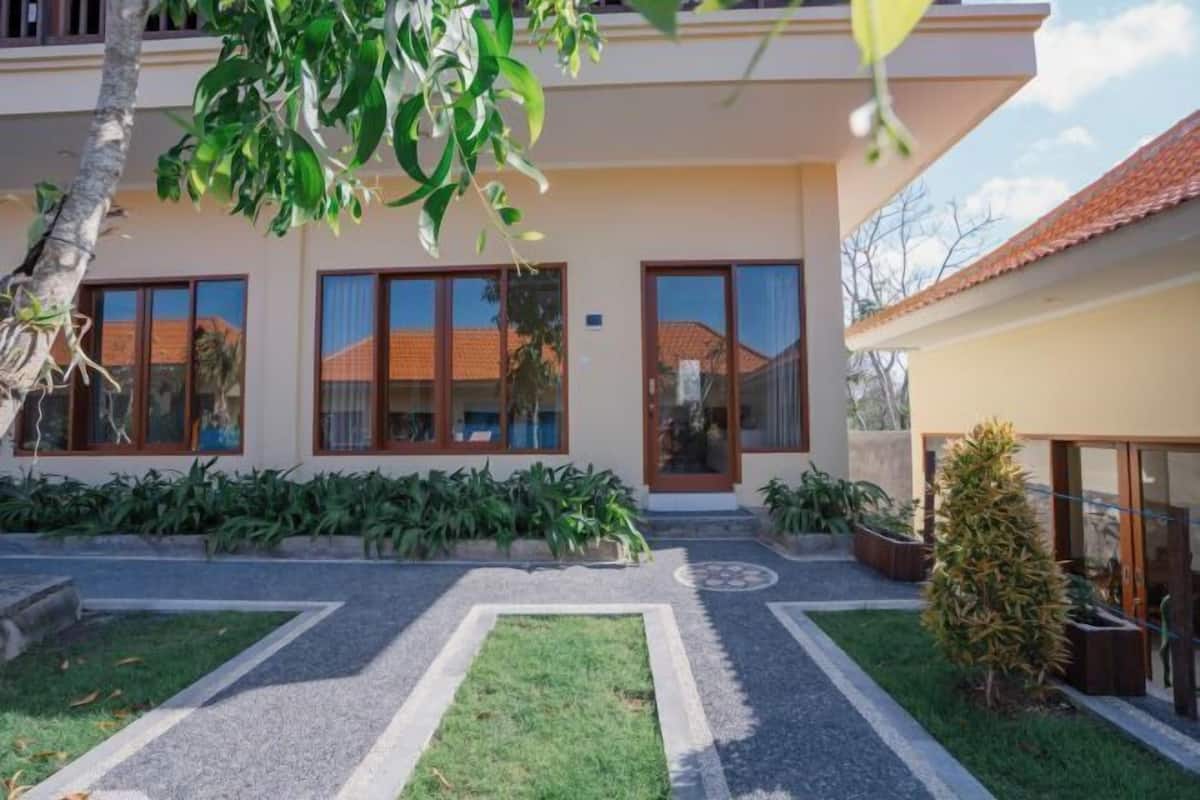 A modern two-story house with a well-maintained garden, large windows, and a tiled roof.