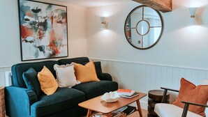 Ein modernes Wohnzimmer mit einem dunkelgrünen Sofa, einem Holztisch und einem runden Spiegel an der Wand.