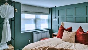 Ein Schlafzimmer mit einem großen Bett, einem Fenster, einem Heizkörper und einem Kleiderhaken.