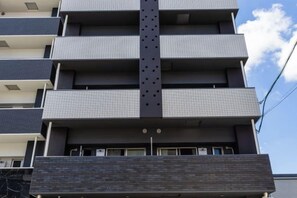 Een meerhoog gebouw met een centrale verticale structuur, balkons op elke verdieping en een plat dak.