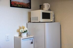 A small kitchenette with a microwave and a refrigerator. - Bainan Service Apartment (Osaka)