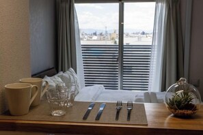 A neatly arranged breakfast table with a view of the city through the window. - Bainan Service Apartment (Osaka)
