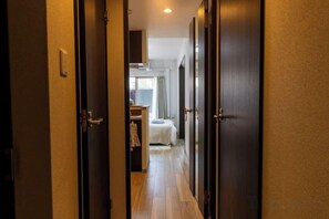 A hallway leading to a bedroom with a bed and a nightstand. - Bainan Service Apartment (Osaka)