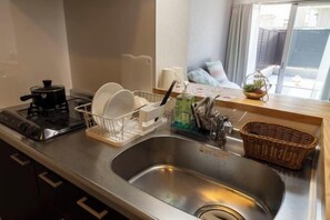 Une cuisine équipée d’un évier en acier inoxydable, d’une cuisinière électrique noire, d’un égouttoir et d’un panier en osier.