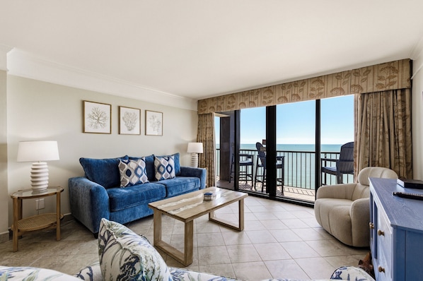 A living room with a sofa, coffee table, and a view of the ocean.