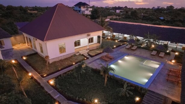 Une grande maison avec une piscine, entourée d’un jardin bien éclairé et d’un espace de détente.