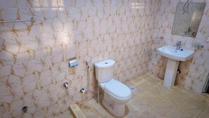 Une salle de bain avec des toilettes, un lavabo et des murs décorés d’un motif imitant le marbre.
