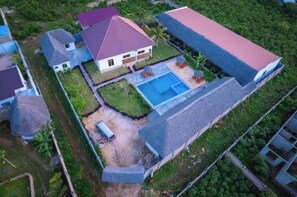 Vista aérea de una propiedad residencial con piscina, un amplio espacio cubierto y varias casas.